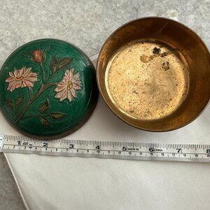 This vintage trinket box features a brass base with a vibrant raised enamel flor
